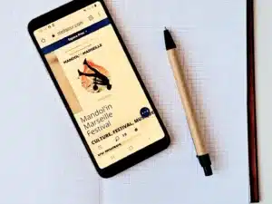 Carnet COSMA vue intérieure sur pages avec stylo en bois et téléphone allumé.