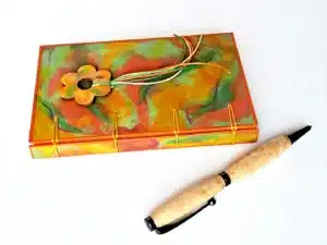 Carnet VENCE vue recto et dos à plat avec marque-pages fleur en bois peint et stylo en bois.